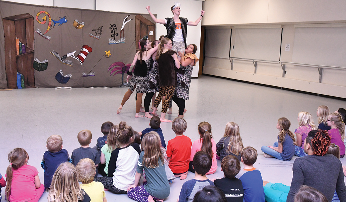Five student dancers hoist a sixth in the air, in front of an audience of school children, as part of the StrikeTime Dance Theatre's production which brings to life a Dr. Suess story.
