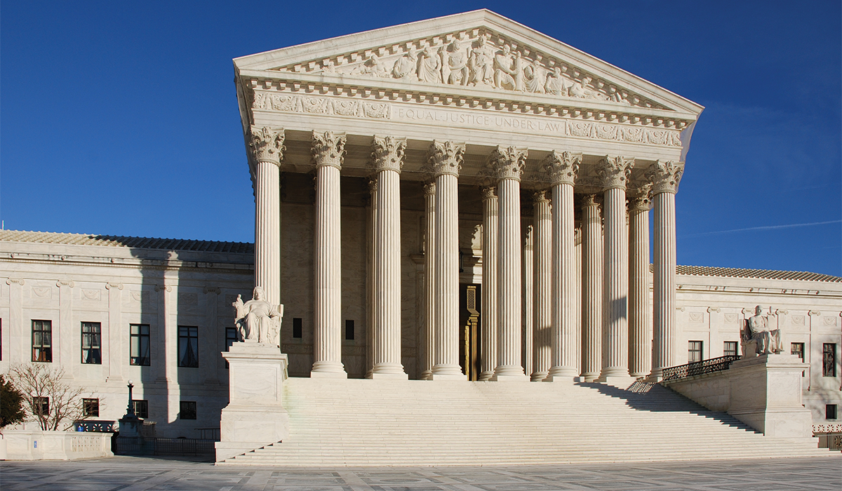 United States Supreme Court Building on a sunny day, with blue cloudless sky in the background. The Supreme Court Building is built in the Neoclassical style. The public façade is made of marble quarried from Vermont, and features 24 columns.
