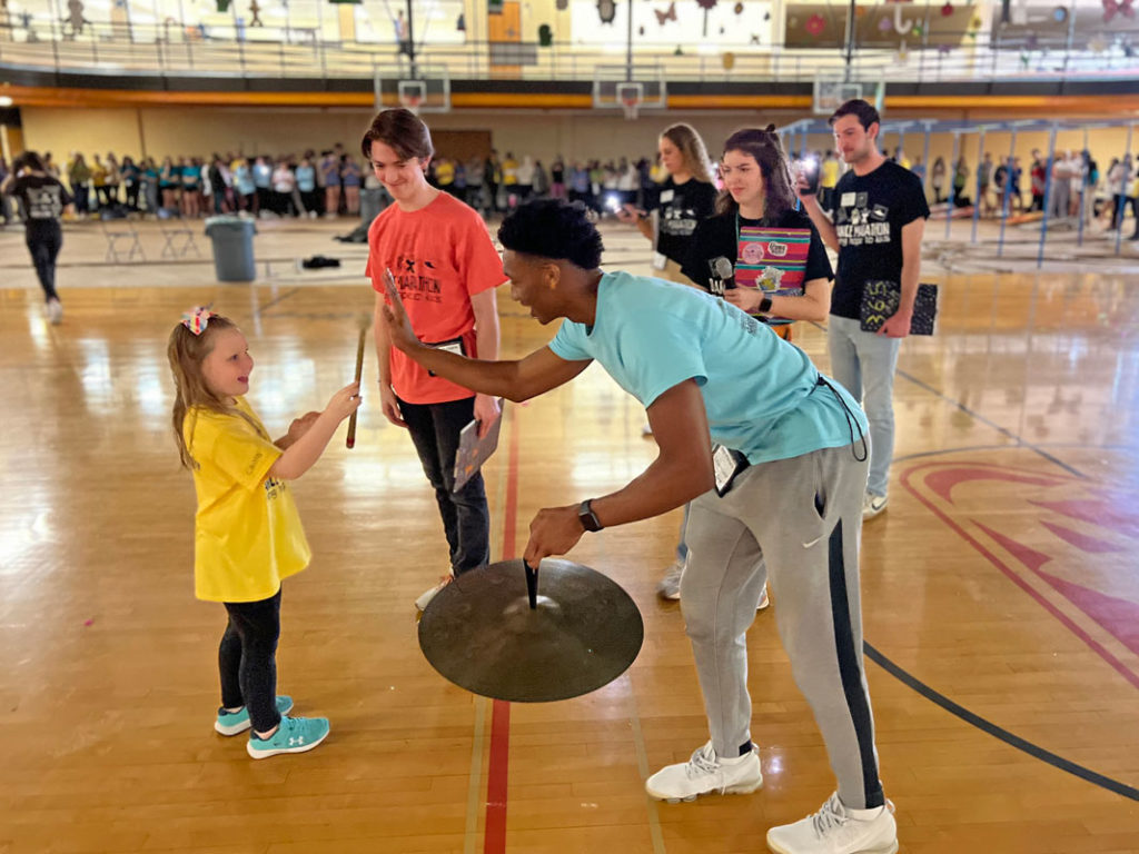 Dance Marathon students playing with a percussion cymbal with one of the little kids.