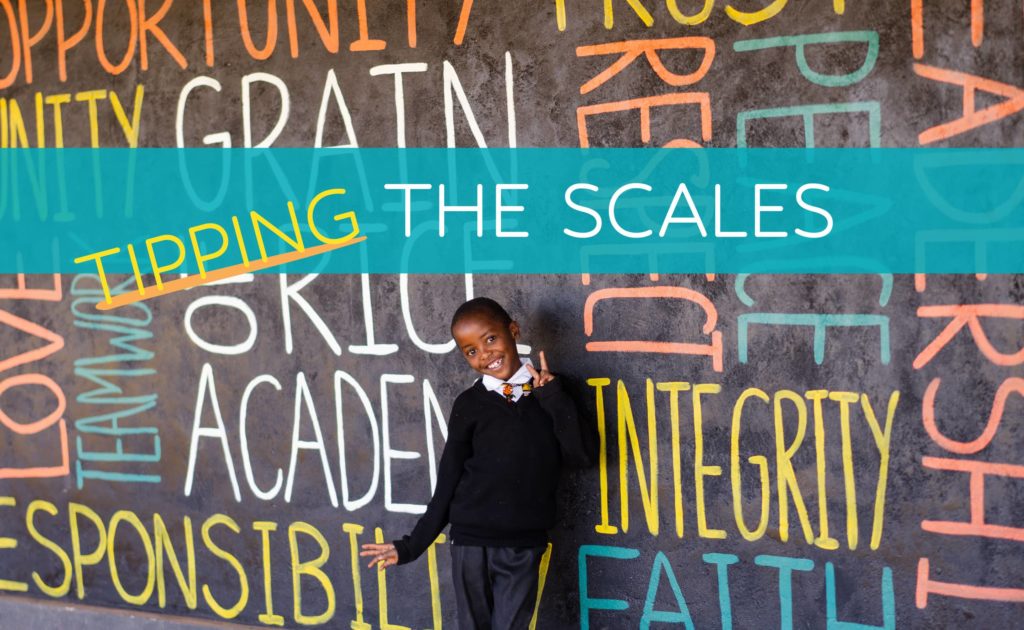 Child smiling in front of a wall decorated with positive words and character traits.