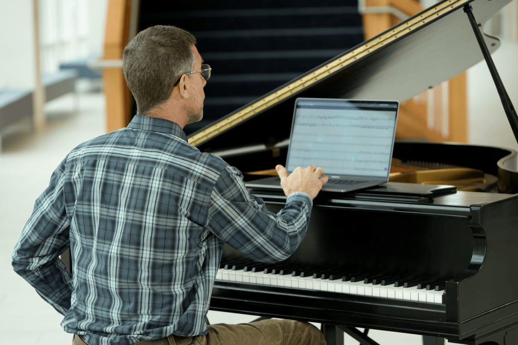 Dr. Matt DeJongh, Professor of Computer Science, seated at a piano with a laptop